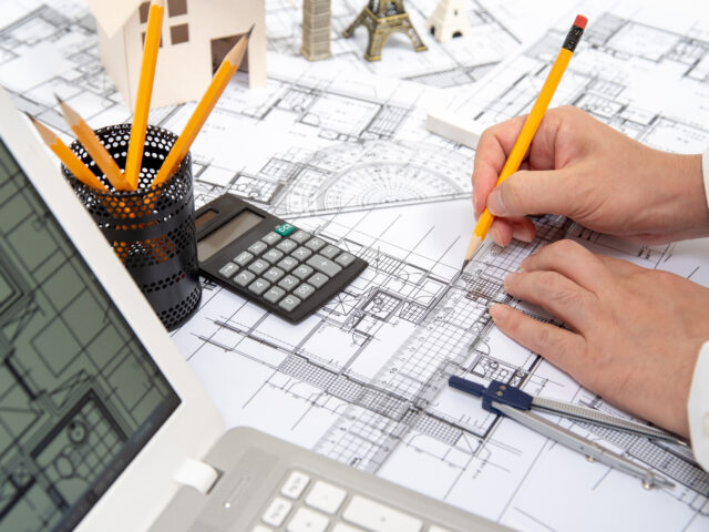 The hand of a male architect drawing a design using a pencil.